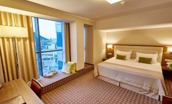 a hotel room with a large bed , a window seat , and a view of the city at Central Plaza Hotel
