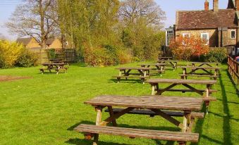 a grassy field with several picnic tables and benches , providing a pleasant outdoor setting for a gathering at The Bell Inn