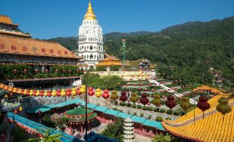 a large white temple surrounded by green trees and mountains , with colorful lanterns hanging in the foreground at Eureka Hotel Penang