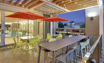 an outdoor dining area with a long table surrounded by chairs and an open fireplace at Home2 Suites by Hilton Hagerstown