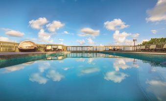 a large outdoor swimming pool surrounded by buildings , with a blue sky above the pool at Lime Tree Bay Resort