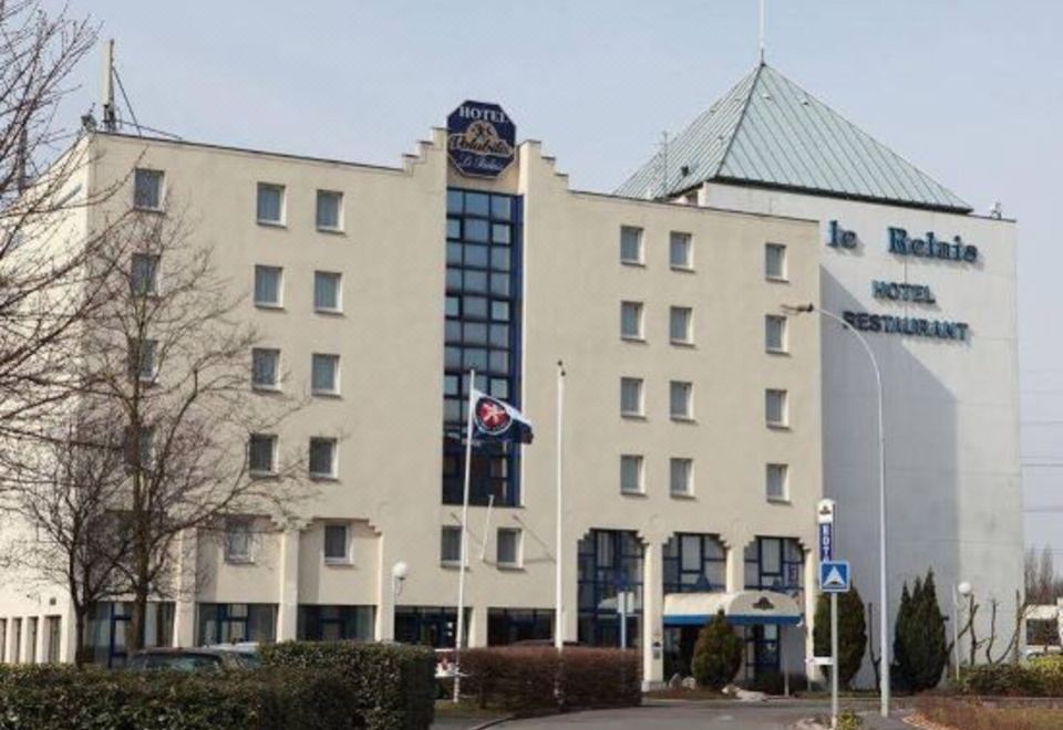 "a modern hotel building with a sign reading "" le balon "" and flags flying in front , under a clear blue sky" at Ibis Styles Lille Marcq-en-Baroeul