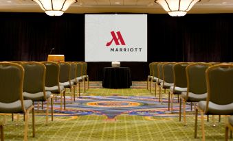 a large conference room with a stage , chairs arranged in rows , and a screen displaying the marriott logo at Washington Dulles Airport Marriott