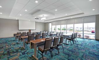 a conference room with rows of chairs arranged in a semicircle and a projector on the wall at Home2 Suites by Hilton Lawrenceville Atlanta Sugarloaf