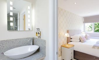 a bathroom with a sink and mirror , next to a bedroom with a bed and nightstand at The Orange Tree Thornham