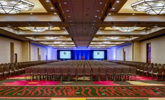a large conference room with rows of chairs and two large screens on the stage at DoubleTree by Hilton Seattle Airport
