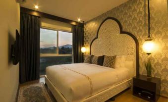 a large bed with a white headboard and multiple pillows is situated in front of a window at Palette the Grand Morocc Hotel