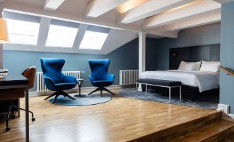 a modern bedroom with blue walls , wooden floors , and a bed , along with two chairs and a table at Radisson Blu 1919 Hotel Reykjavik
