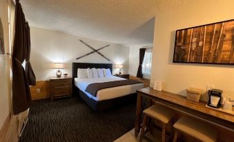 a large bed with a brown and white striped blanket is in the middle of a room with a desk and chairs at Shasta Inn