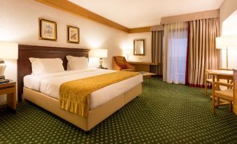 a large bed with a gold blanket is in the middle of a room with green carpeting at Hotel Estoril Eden