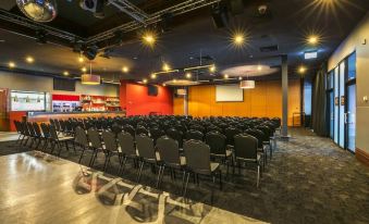 a large conference room with rows of chairs arranged in a semicircle , and a podium at the front at Nightcap at Matthew Flinders Hotel