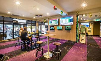 a bar with multiple televisions mounted on the wall , along with several stools for patrons to sit on at Nightcap at Glengala Hotel