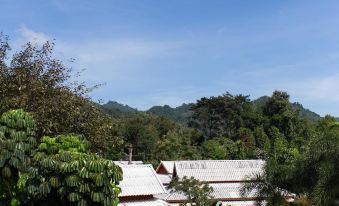 a beautiful view of a mountain range with a white building in the foreground and green trees surrounding it at Poonyamantra Resort