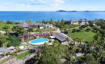 an aerial view of a resort with a large pool surrounded by lush greenery and a view of the ocean in the background at Kokomo Private Island Fiji