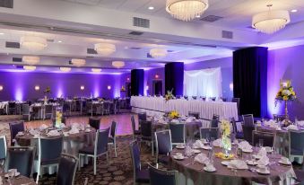 a large banquet hall with multiple tables and chairs set up for a formal event , possibly a wedding reception at DoubleTree by Hilton Hotel Syracuse