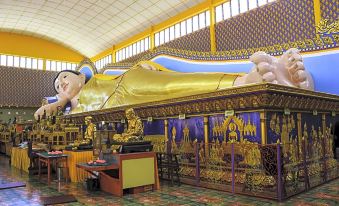 a large , ornate reclining buddha statue is displayed in a room with colorful walls and cabinets at Tropics Eight Suites