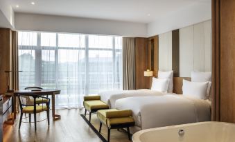 a modern hotel room with a large bed , bathtub , and dining area , all situated near a window at Pullman Changbaishan Resort
