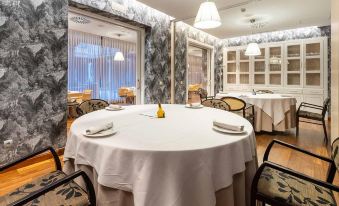 a well - decorated dining room with a round table surrounded by white tablecloths and chairs , creating a elegant atmosphere at Castilla Termal Olmedo