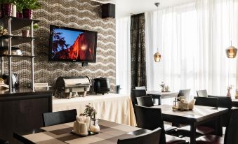 a restaurant with a large dining table , several chairs , and a television mounted on the wall at Diplomat Hotel