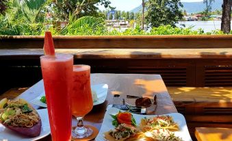 a table with a plate of food and two glasses filled with pink liquid , set in front of a beautiful view at Rikitikitavi