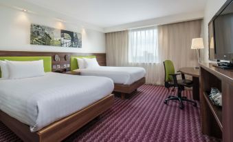 a modern hotel room with two beds , white bedding , and purple carpeting , along with a desk and chair at Hampton by Hilton Birmingham Broad Street