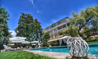 a large swimming pool is surrounded by lounge chairs and umbrellas , with a building in the background at Blue Dream Hotel