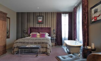 a luxurious hotel room with a large bed , a bathtub , and a bathroom with a bathtub at Malmaison Dundee