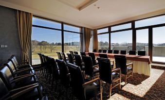 a conference room with black chairs arranged in rows , and large windows offering views of the outdoors at Hotel International