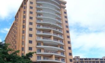 a tall building with multiple balconies and a car parked in front of it , under a blue sky at Venezuela Marriott Hotel Playa Grande