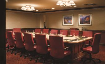 a conference room with a long wooden table and red chairs , set up for a meeting at DoubleTree by Hilton Hotel Cincinnati Airport