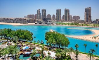 a large body of water with palm trees and a city skyline in the background at The Ritz-Carlton, Doha