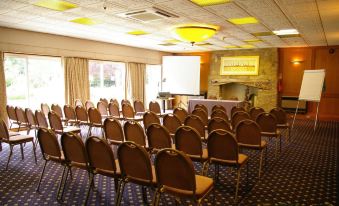 a conference room with rows of chairs arranged in a semicircle , and a projector mounted on the wall at Alton House Hotel