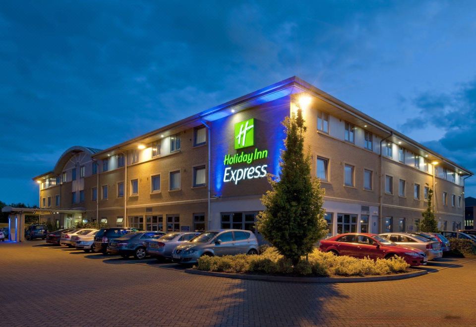 an exterior view of a holiday inn express hotel with multiple cars parked in front at Holiday Inn Express East Midlands Airport