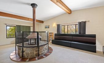 a spacious living room with a large stone fireplace , wooden beams on the ceiling , and a comfortable couch at Discovery Parks - Jindabyne