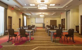 a large conference room with multiple rows of chairs arranged in front of a long table , and a projector screen on the wall at Hilton Garden Inn Uniontown
