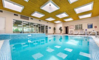 an indoor swimming pool with a yellow ceiling , surrounded by glass windows and a tiled floor at Quality Inn Monterrey la Fe