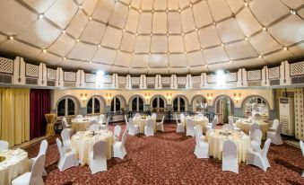 a large , round room with a high ceiling and white walls has several tables set for dining at Marbella Resort