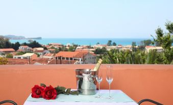 a table with a wine bottle and two glasses on it , overlooking a cityscape and ocean at Lena Mare Boutique Hotel