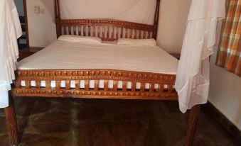 a wooden bed with white sheets and pillows , located in a room with dark wood flooring at Blue Rooms