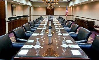a long wooden conference table with chairs , wine glasses , and american flags in a room with a chandelier and american flag hanging from the ceiling at Holiday Inn Wilmington