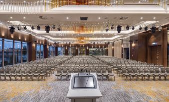 a large conference room with rows of chairs and a podium in the center , ready for a presentation at DoubleTree by Hilton Skopje