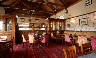 a dining room with wooden tables and chairs arranged for a group of people to enjoy a meal together at Best Western Plus Pastures Hotel