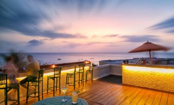a sunset view from a rooftop bar , with two chairs and tables set up for drinks and conversation at Beach View Hotel
