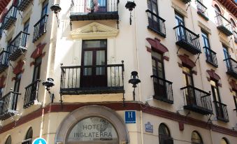 a city street with a tall white building on the left side and a tall brown building on the right side at Hotel Inglaterra