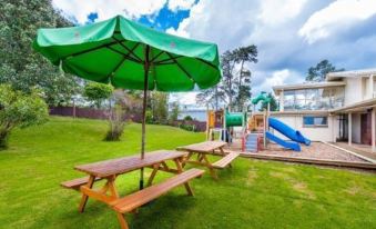 a playground with picnic tables and umbrellas , as well as a slide and other equipment at Poenamo Hotel