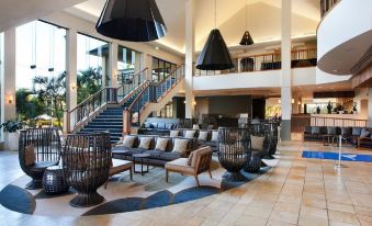 a large hotel lobby with a grand staircase leading to the second floor , filled with comfortable seating and decorative elements at Mercure Gold Coast Resort
