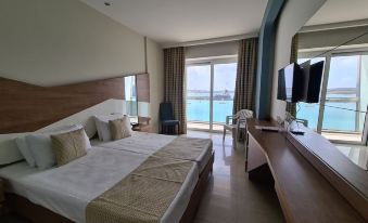 a modern hotel room with a large bed , desk , and sliding glass door leading to a balcony overlooking the ocean at Water's Edge Hotel