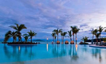 a large swimming pool with palm trees and a view of the ocean in the background at The Westin Playa Bonita Panama