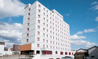 a tall white hotel building with a red stripe on the side , situated in a city at Hotel Wing International Chitose