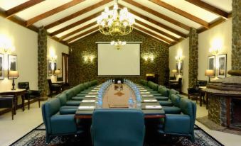 a large conference room with a long table , blue chairs , and a chandelier hanging from the ceiling at Ngorongoro Oldeani Mountain Lodge